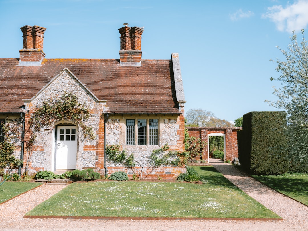 A well-kept stone cottage with a tidy garden path under a blue sky
